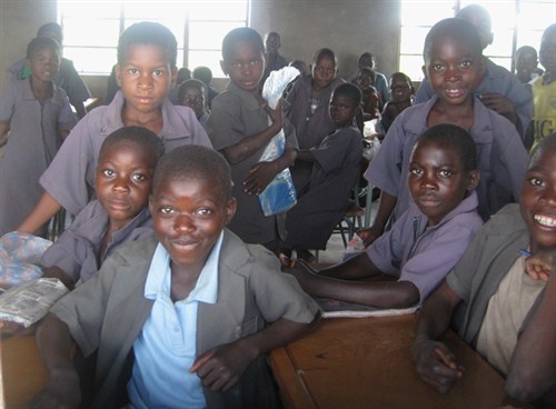 Pupils in a classroom smiling in grey uniform for African Revival school resources